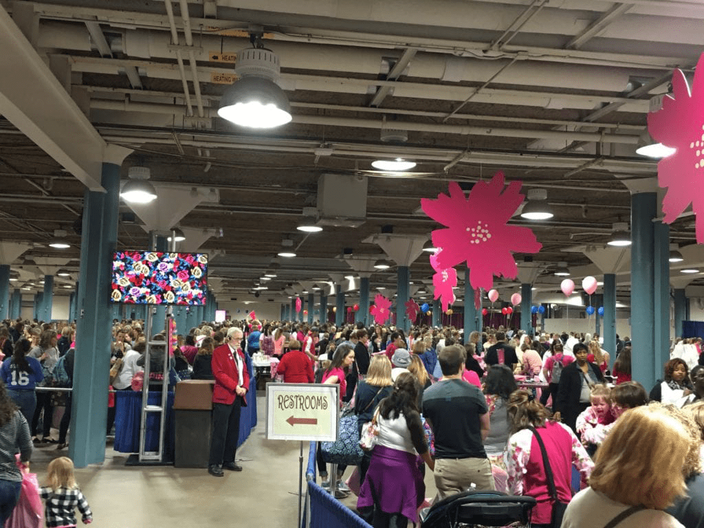 A crowd of people in a building with pink decorations.